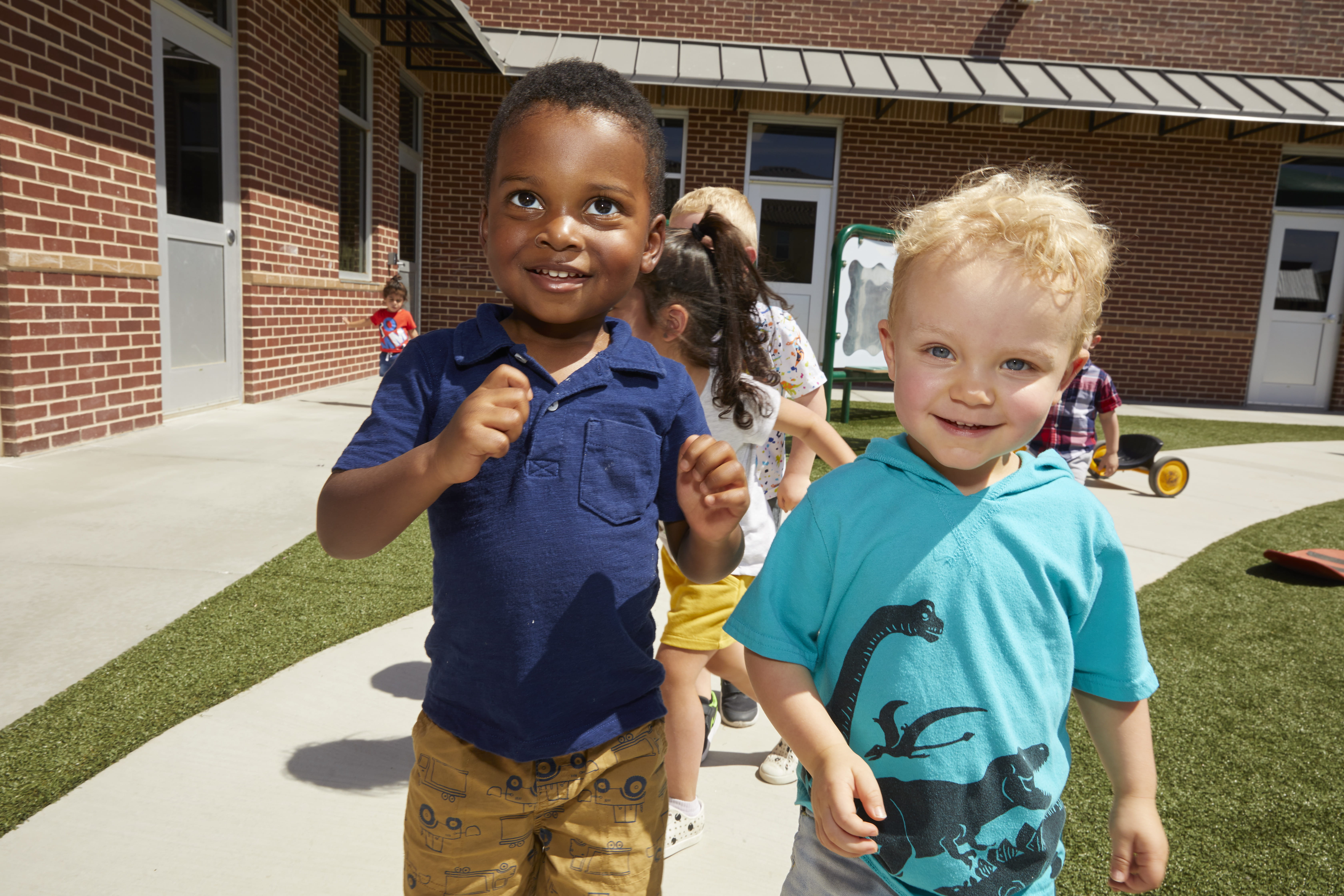Two children smiling at the camera while playing outside