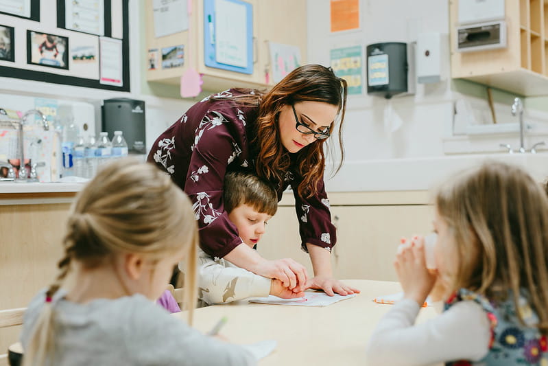 Teacher helping child with craft