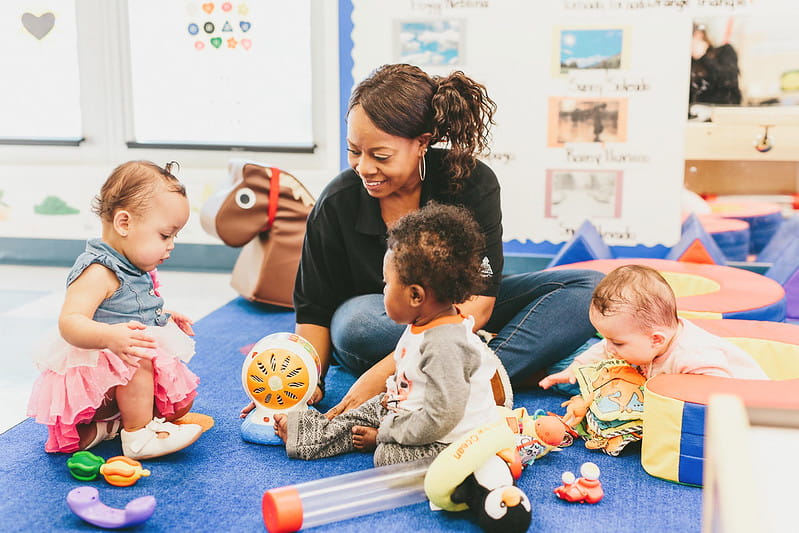 Teacher playing with three infant-aged children