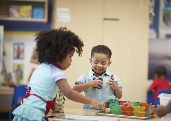 Two children playing with blocks at a table