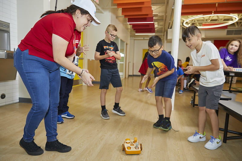 Children and teacher play with robotic car