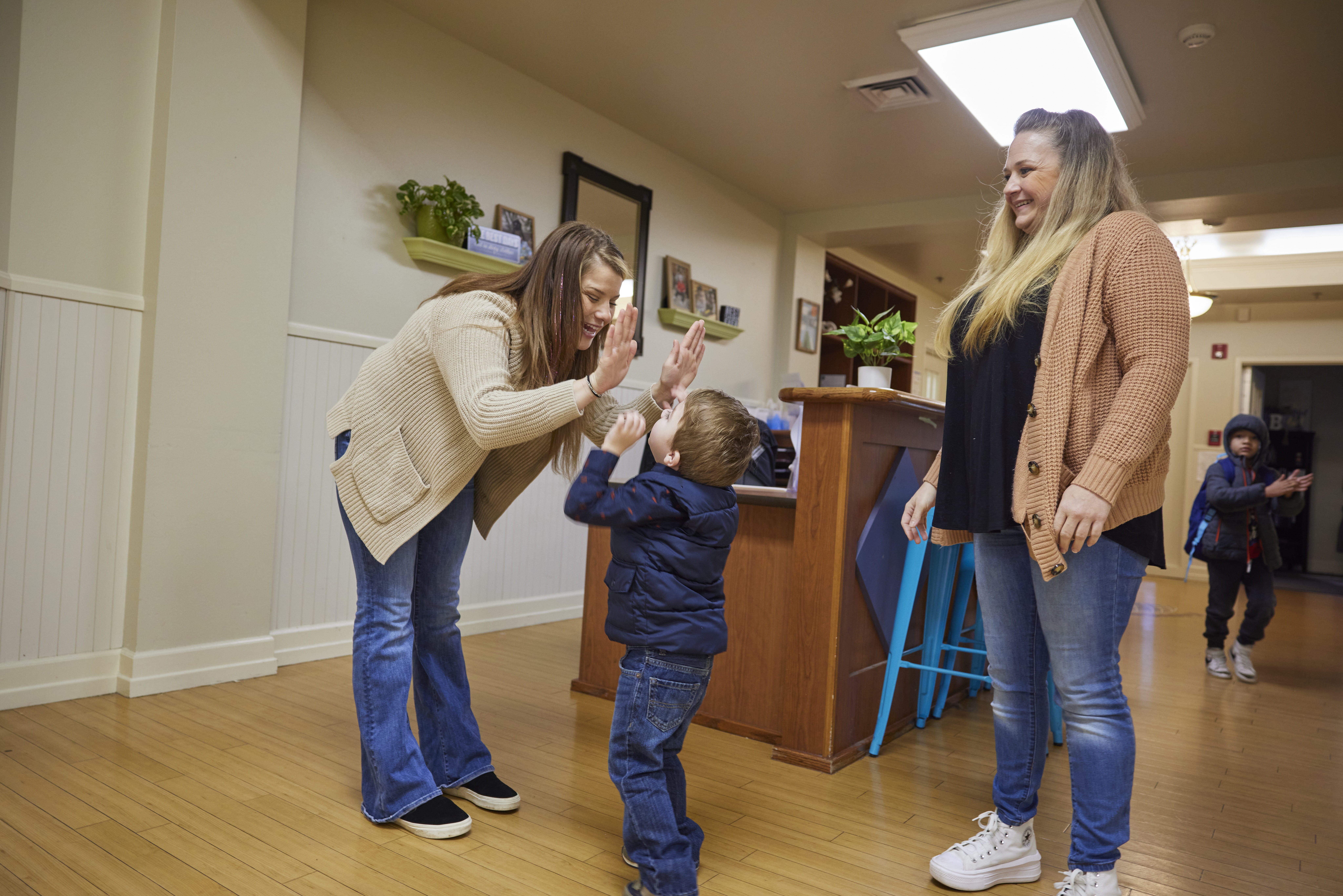 Teacher giving a high-five to a child at child care drop-off