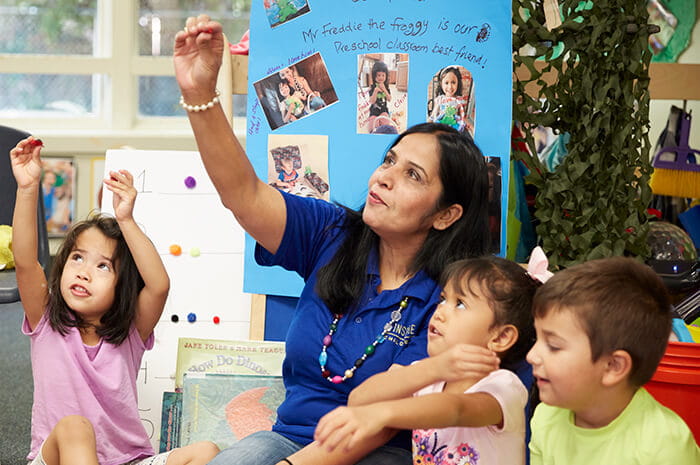 KinderCare teacher with students in classroom