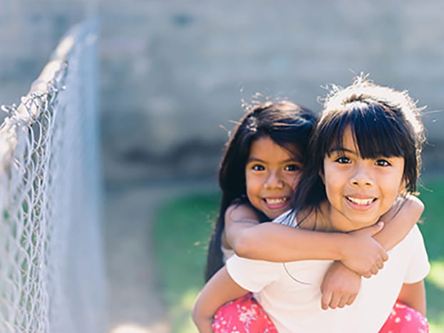 Two young sisters together outside 