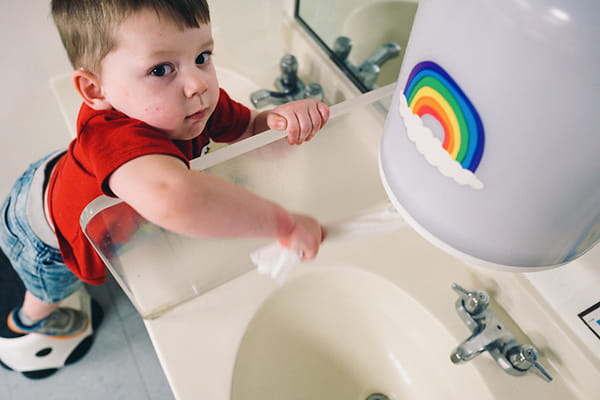 A toddler climbing up to a sink