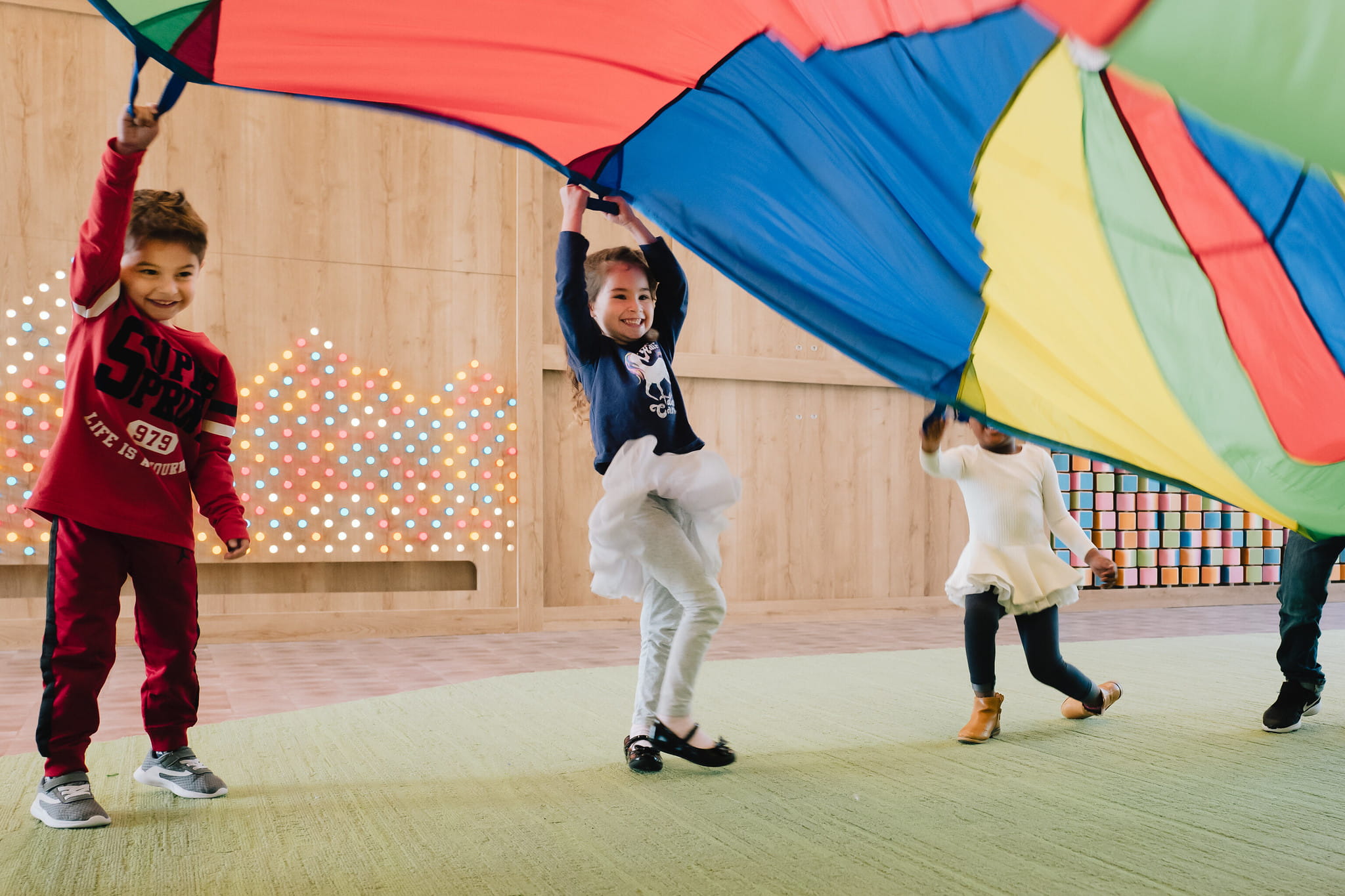 Children playing with a rainbow parachute