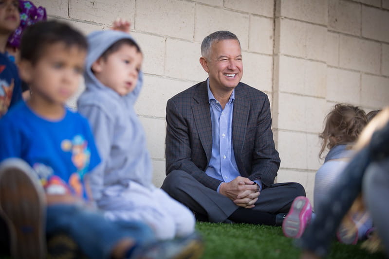 CEO Tom Wyatt sits outside with children in grass