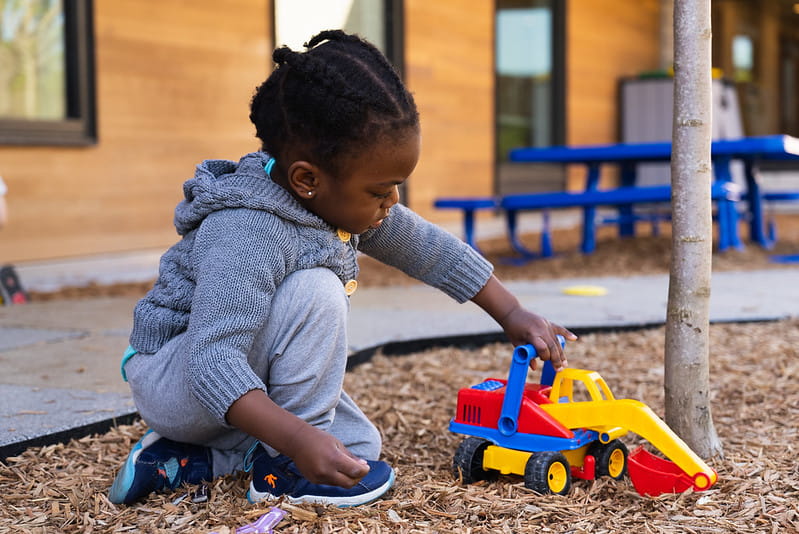 Child playing with toy truck on playground